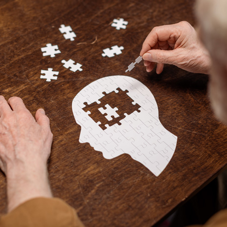 Hands assembling a head-shaped puzzle on a wooden table