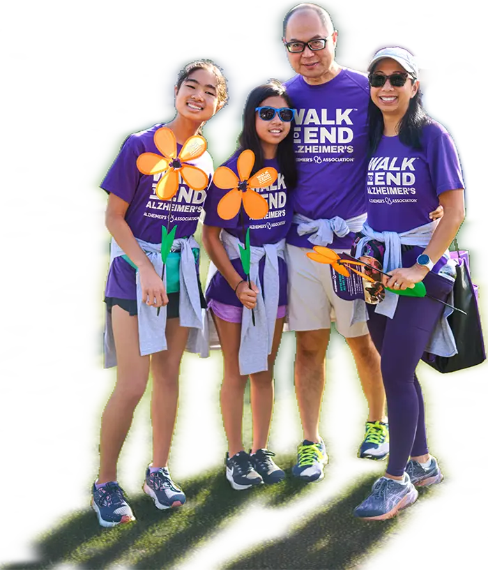 A family in purple Walk to End Alzheimer’s shirts holding colorful flowers