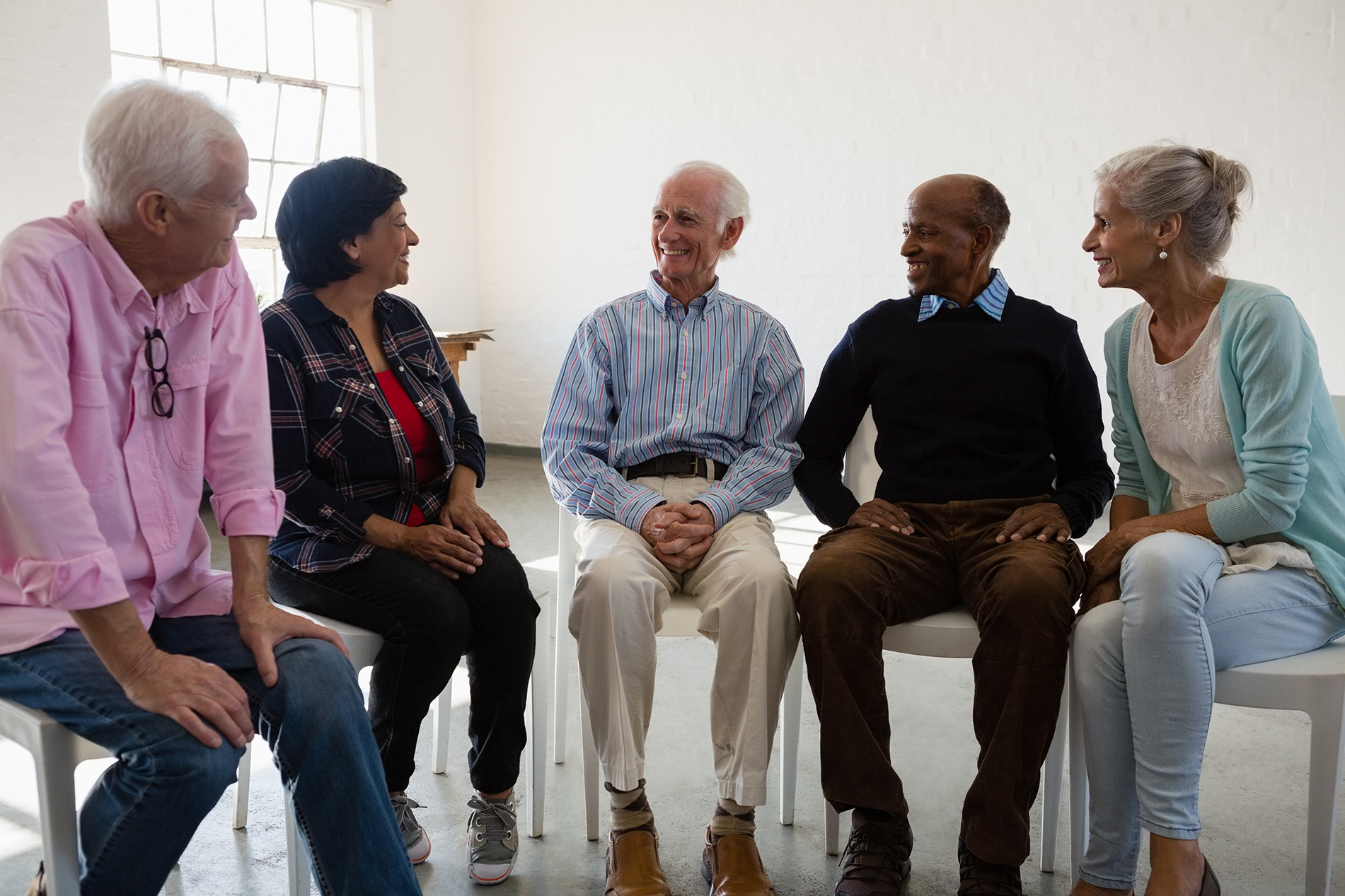 A group of older adults smiling and talking together in a circle