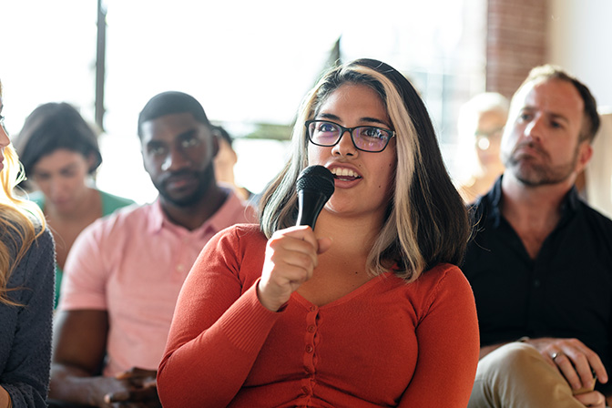 A participant asking a question with a microphone during a group discussion