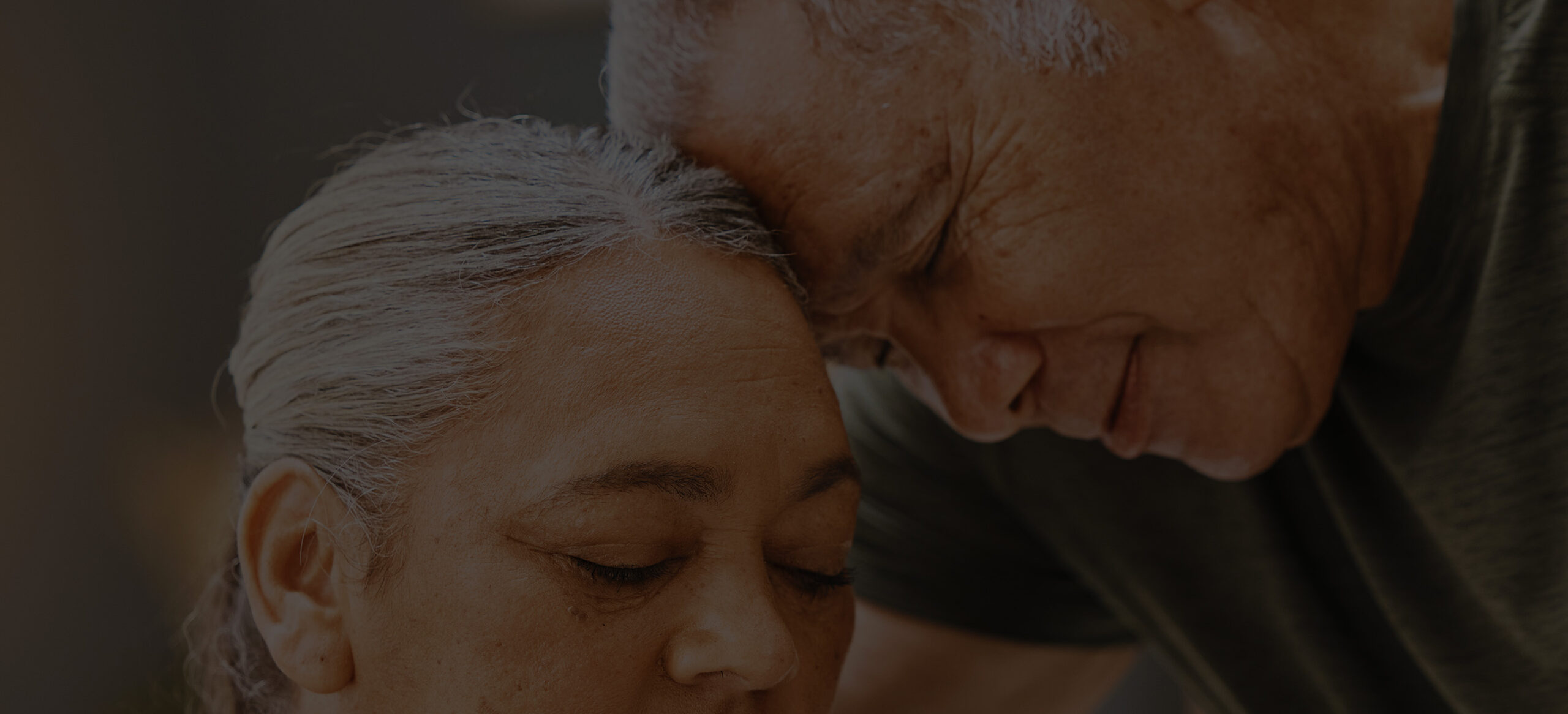 An older couple leaning their heads together in a quiet moment