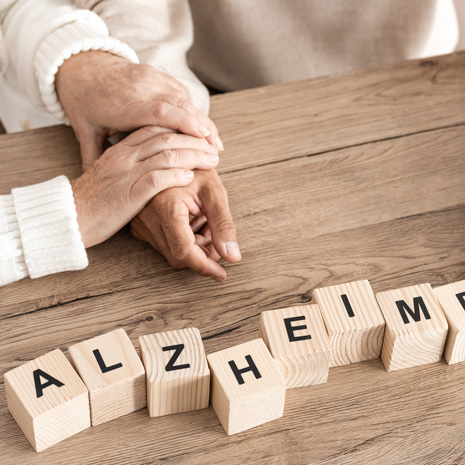 One person gently holding another person’s hand beside wooden letter tiles